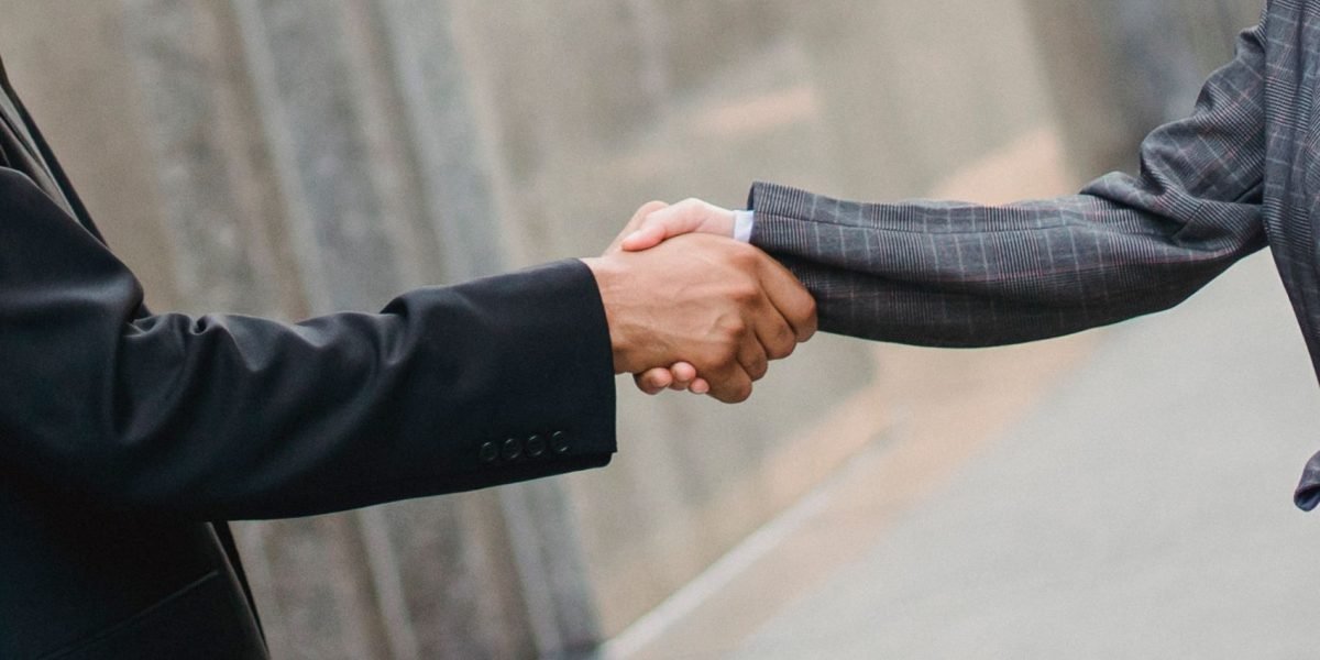 Two business professionals shaking hands, symbolizing the formation of a lasting, trustworthy partnership in real estate investment.